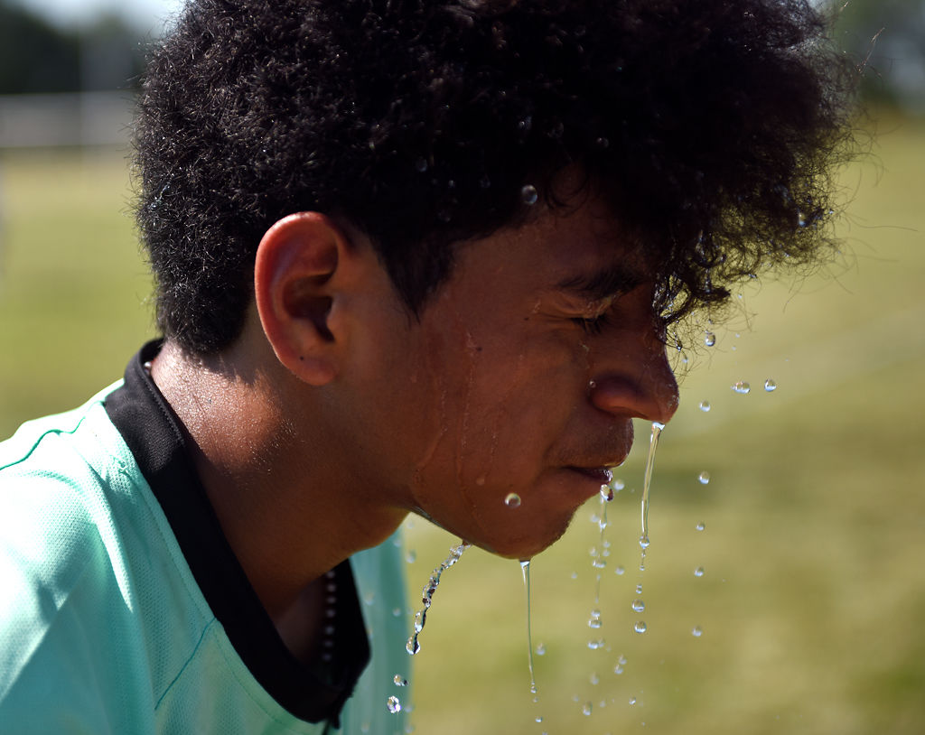 Alexander Hernandez, 14, pours some water from a water bottle